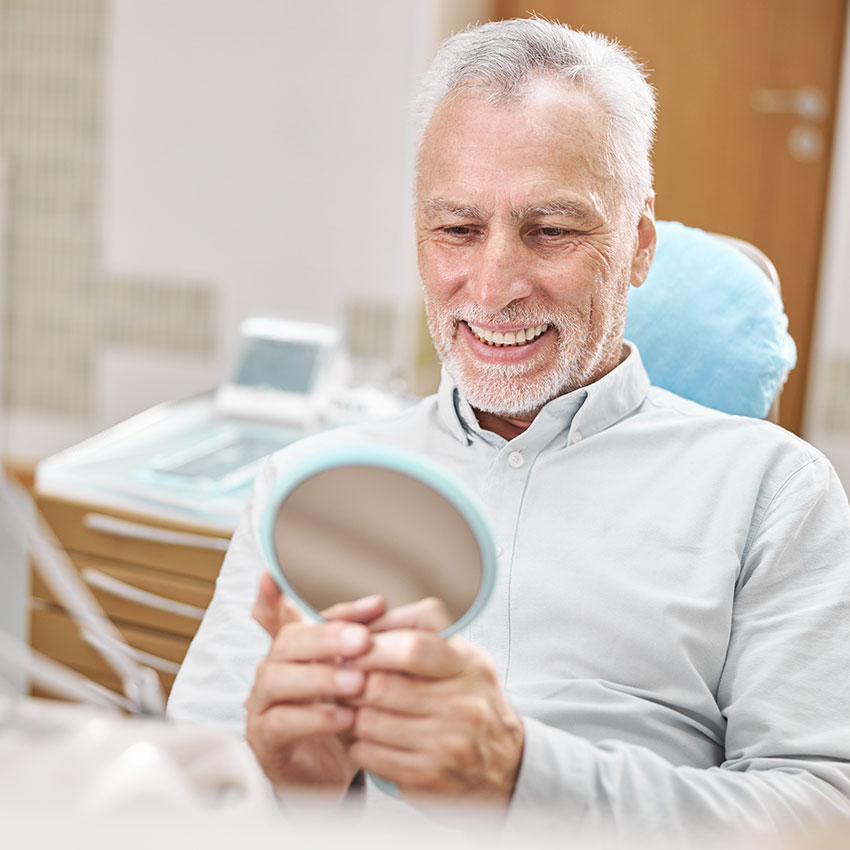 Happy patients smiling in mirror after dental implant therapy in Woodland Hills, CA
